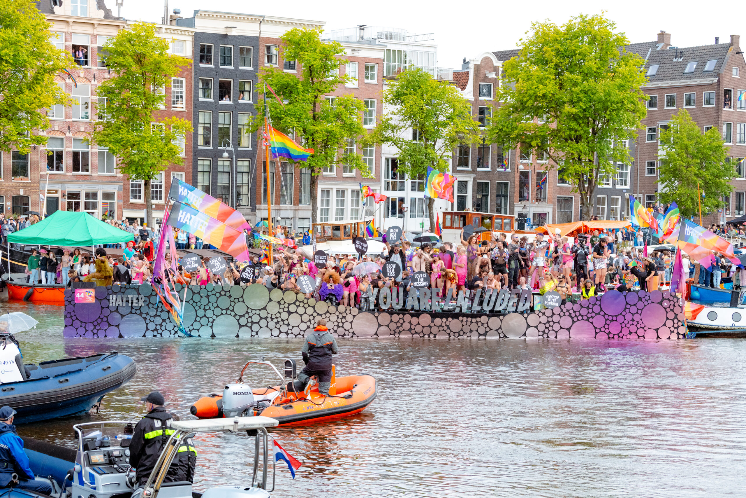 Boot met feestvierders en regenboogvlaggen tijdens de Pride Parade op een Amsterdamse gracht.