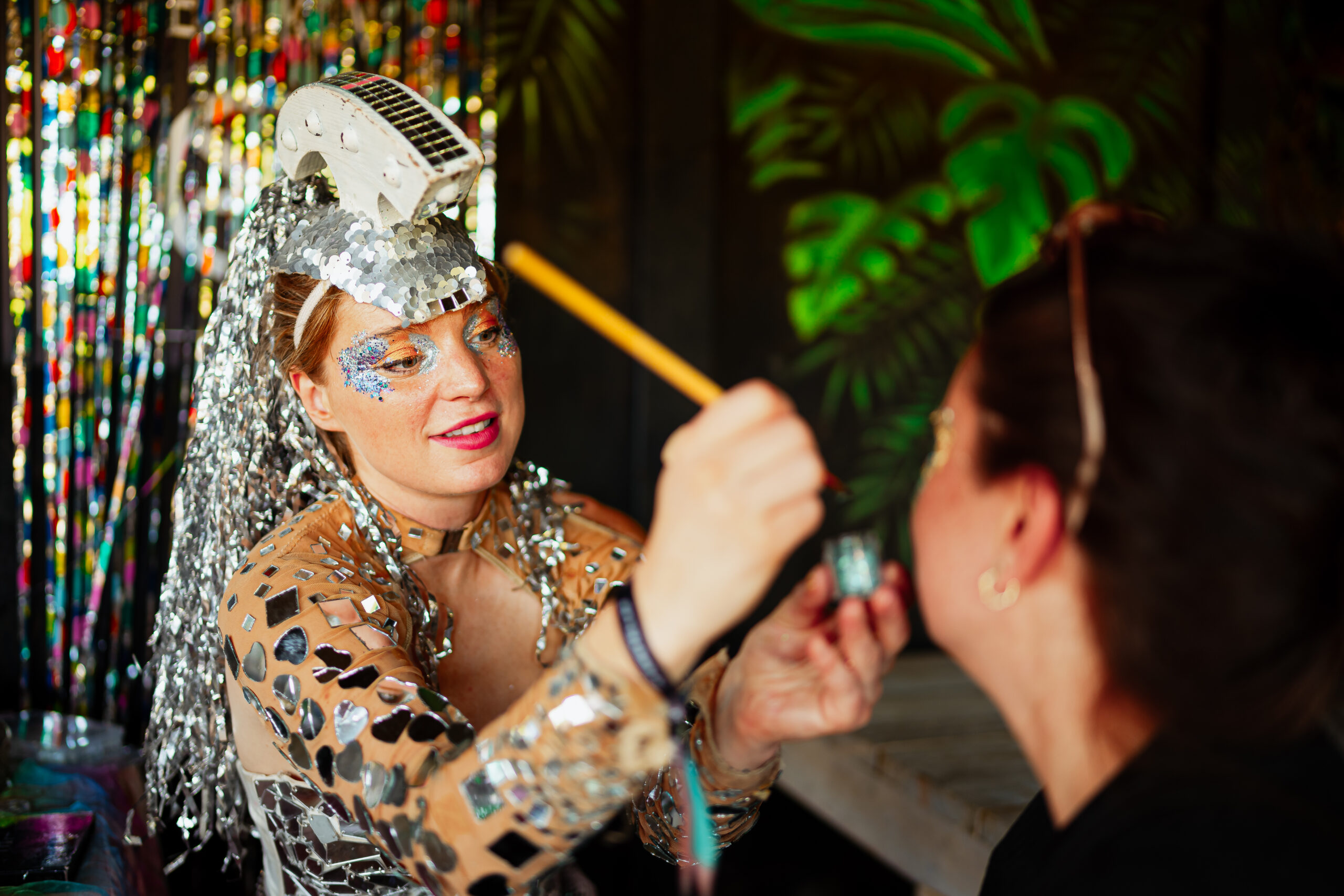 Glitter make-up artiest versiert gezicht van festivalbezoeker.