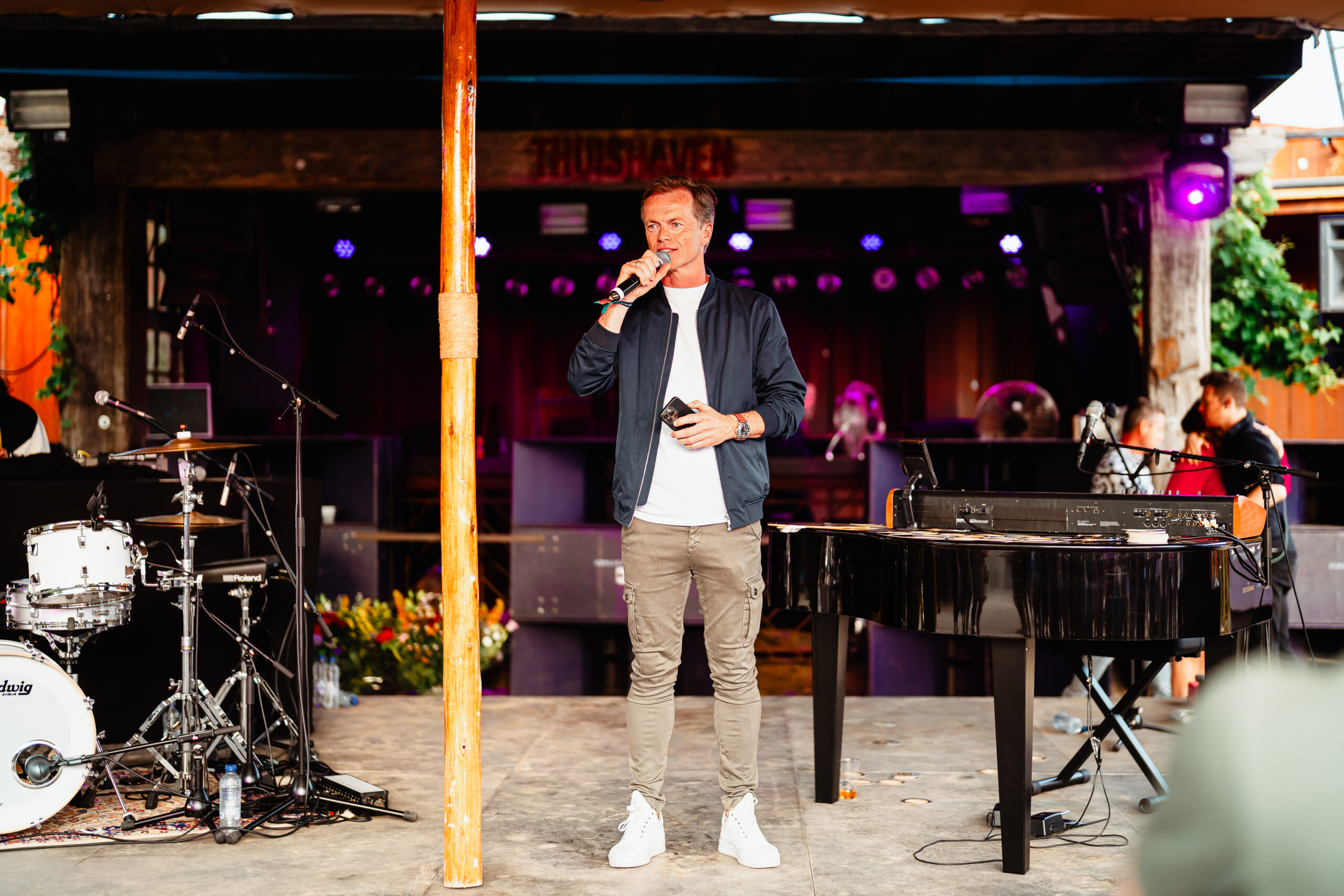 Een spreker op een buitenpodium bij een festival.