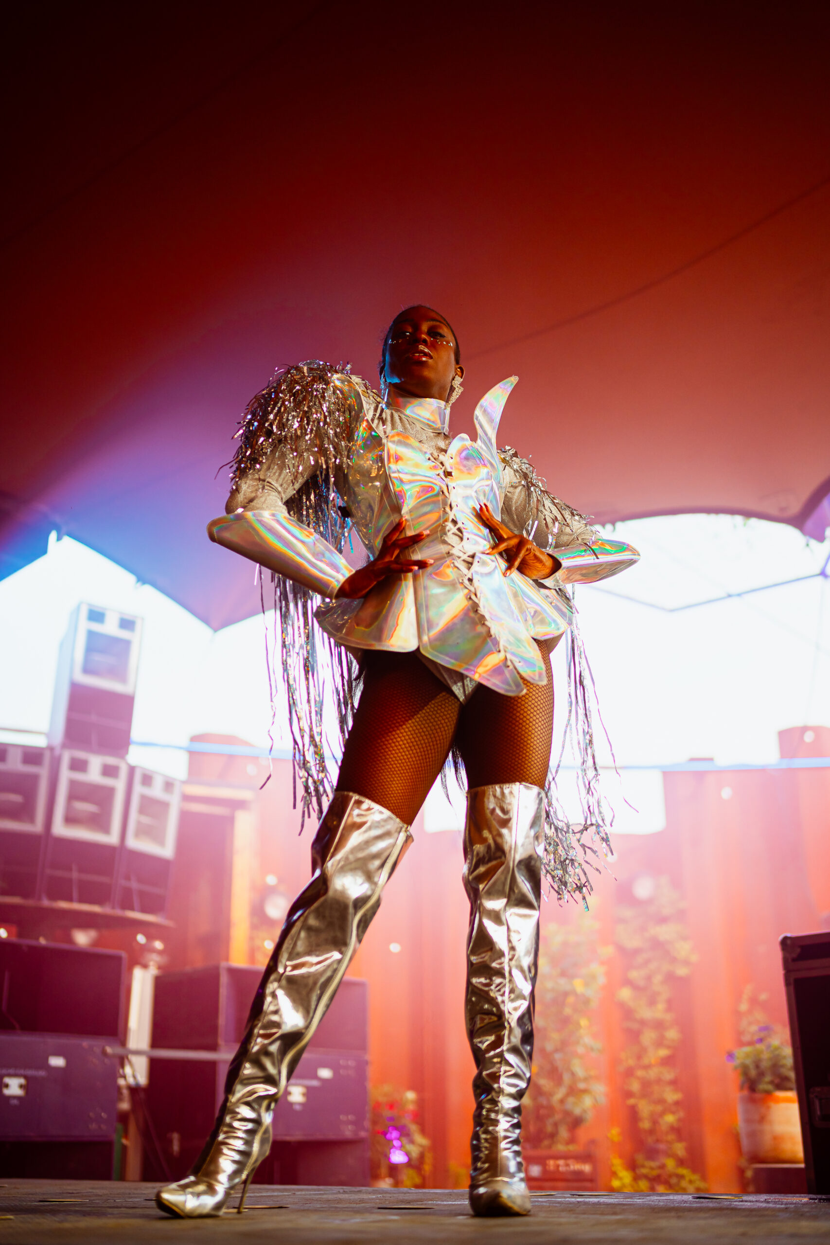 Performer in zilveren, futuristische outfit met hoge laarzen en schouderdetails.