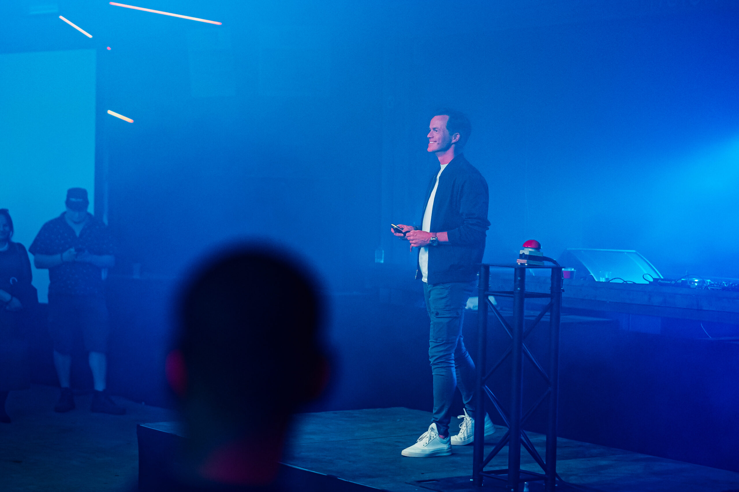 Een spreker op een podium met futuristische blauwe verlichting.