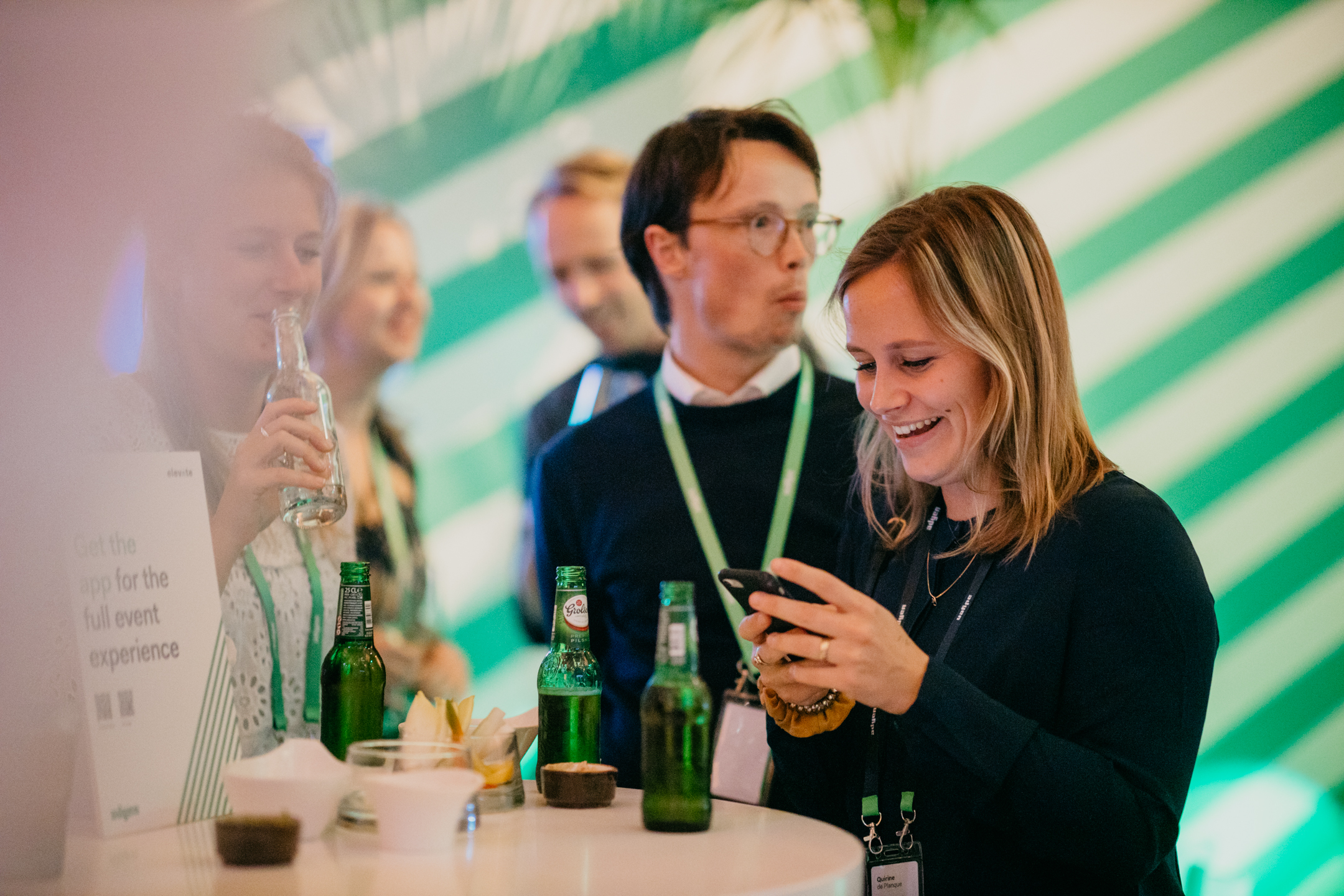 Ontspannen netwerkmoment op een evenement, waar een groep professionals geniet van drankjes en interactie in een stijlvolle setting met groene accenten