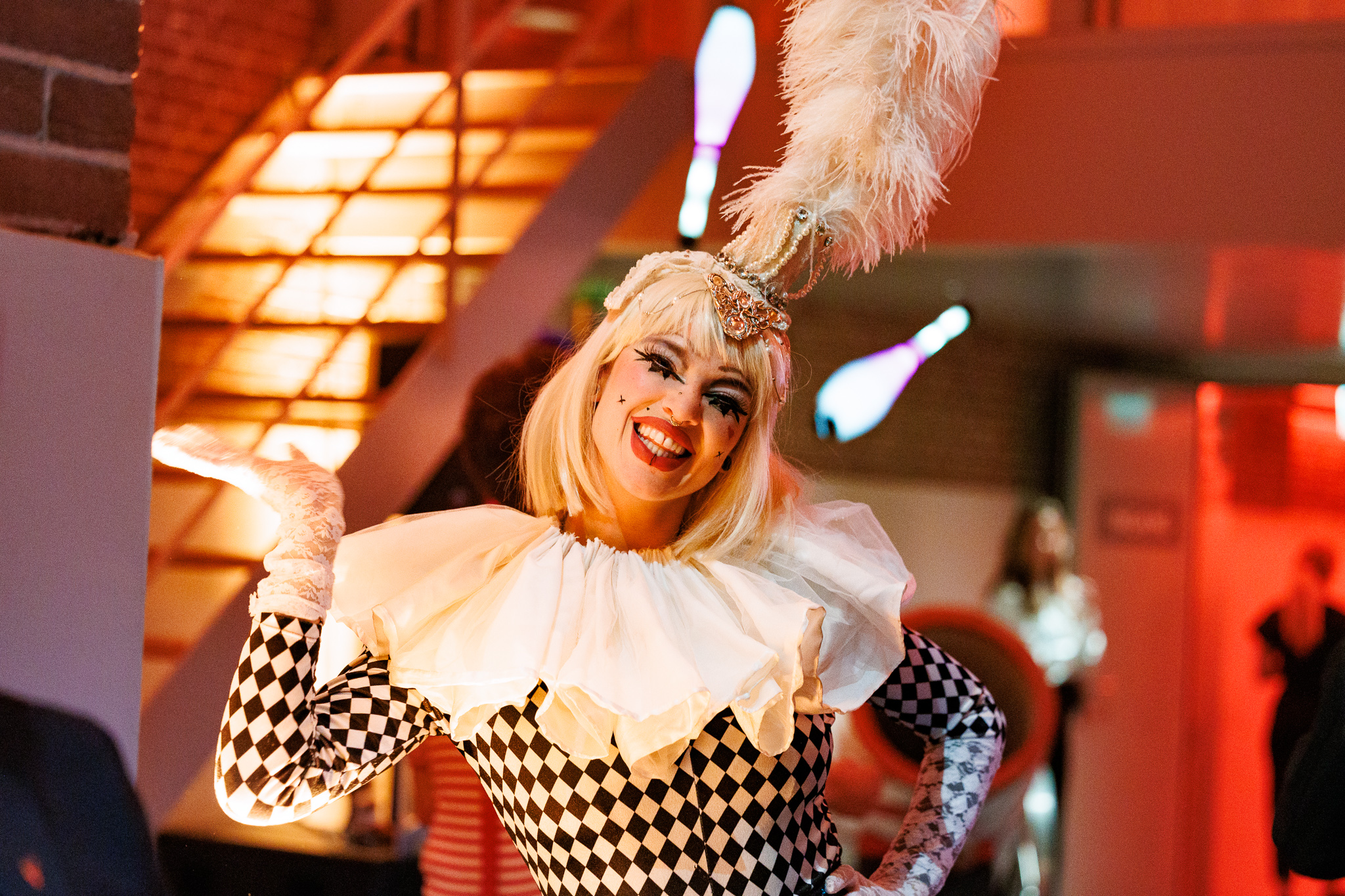 Artiste in een zwart-wit harlekijnoutfit met een feestelijke glimlach tijdens het ANG netwerkevent met circusthema.
