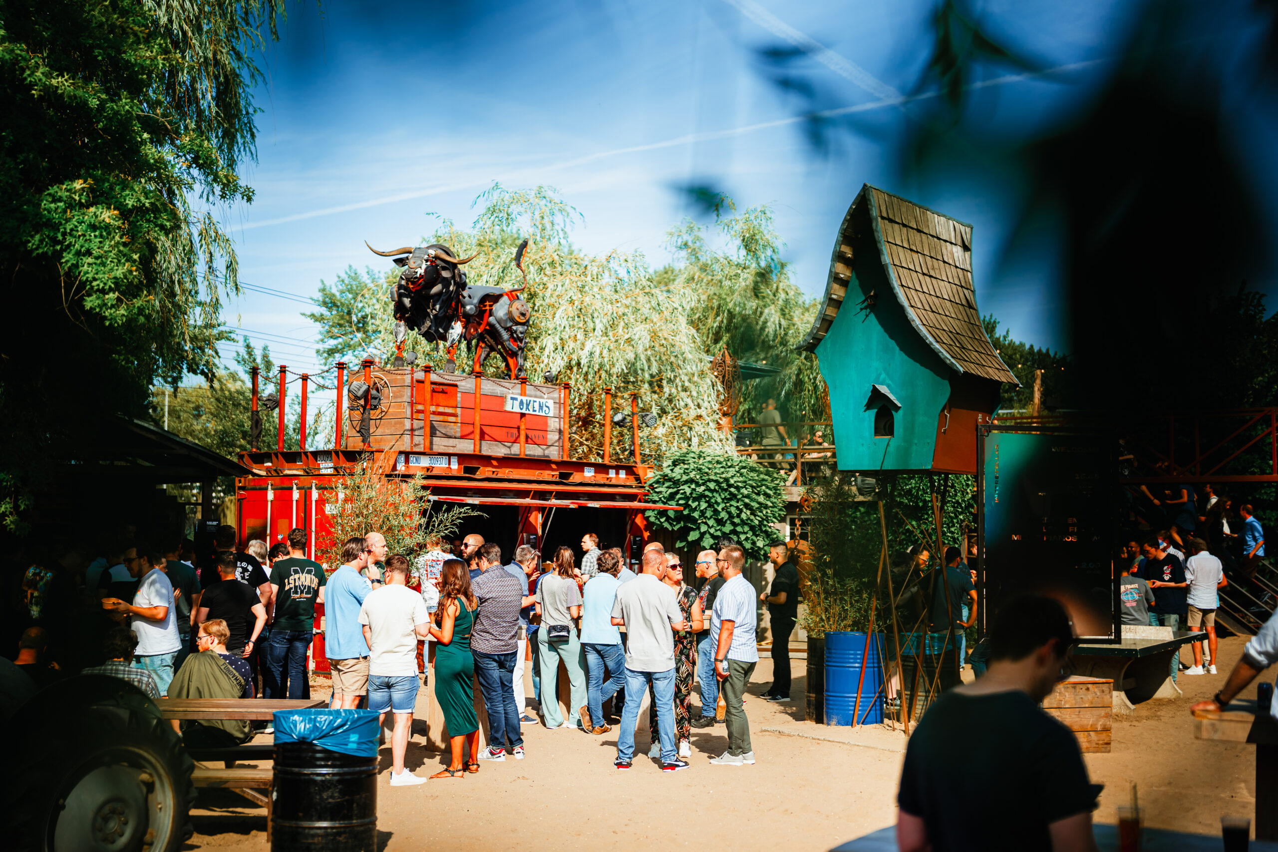 Buitenevenement met een groep mensen, creatieve decoraties en een rode container met stierenbeelden erop
