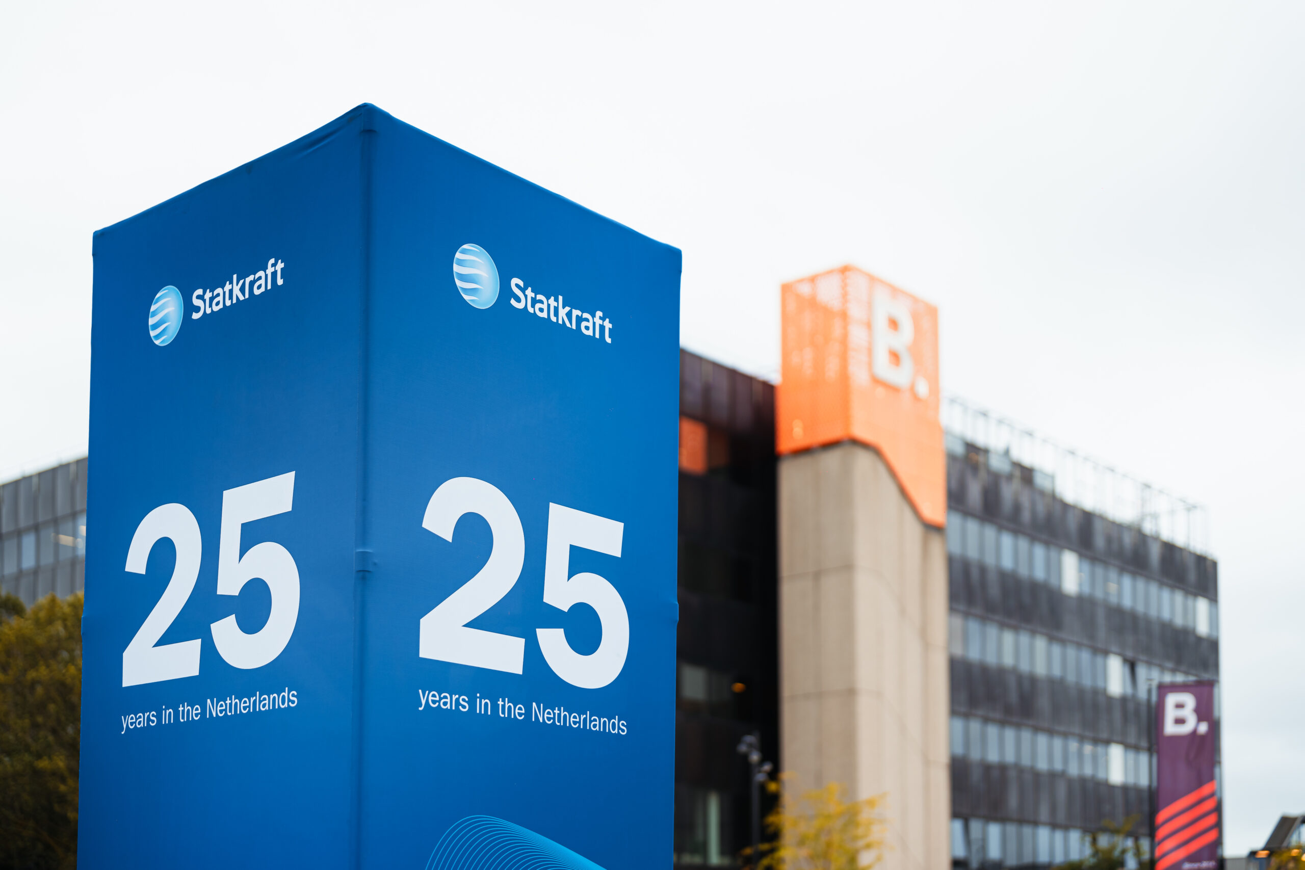Blauw Statkraft 25-jaar banner met kantoorgebouw op de achtergrond tijdens het jubileumevenement in Nederland.