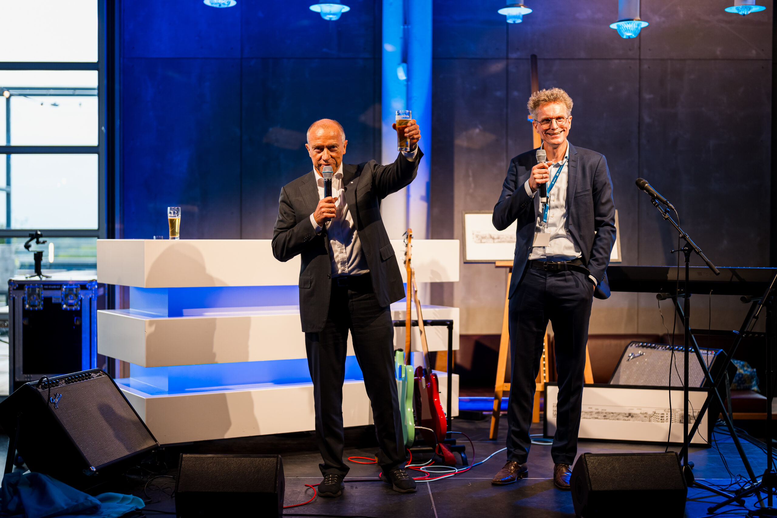 Twee sprekers proosten op het podium tijdens het Statkraft 25-jarig jubileumevenement, georganiseerd door Dutch Standard Events.
