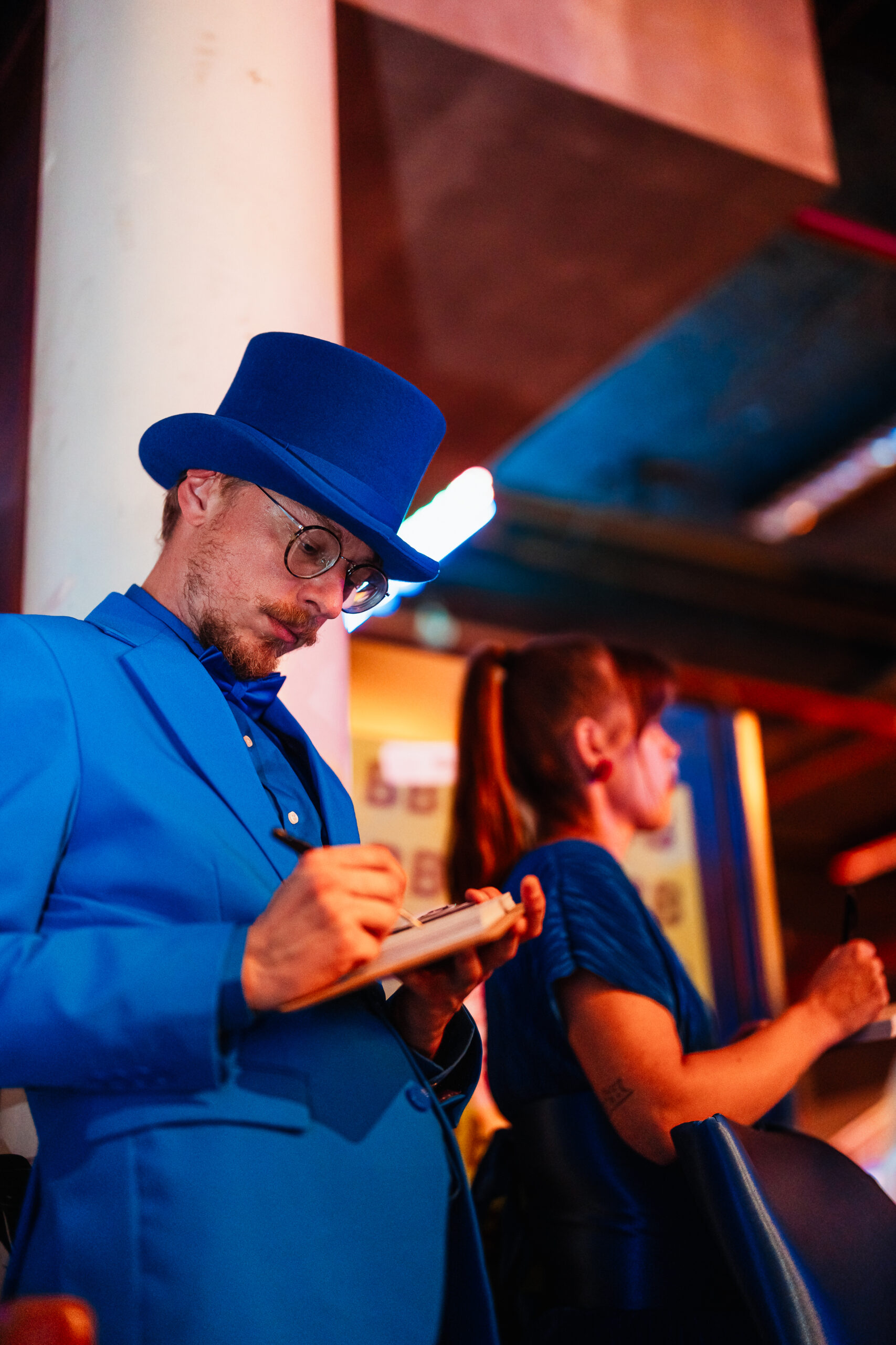 Host in een blauw kostuum maakt aantekeningen tijdens het Statkraft 25-jarig jubileumevenement.