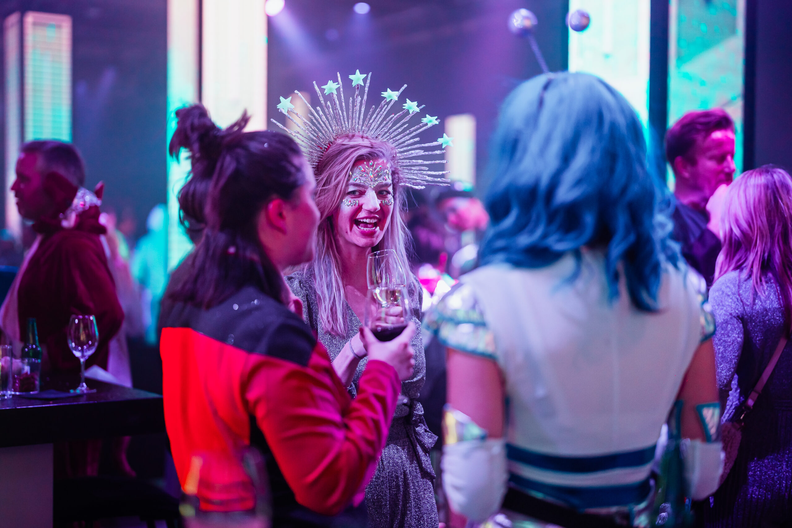 Gasten in opvallende en creatieve thema-outfits tijdens een ruimte-themafeest.