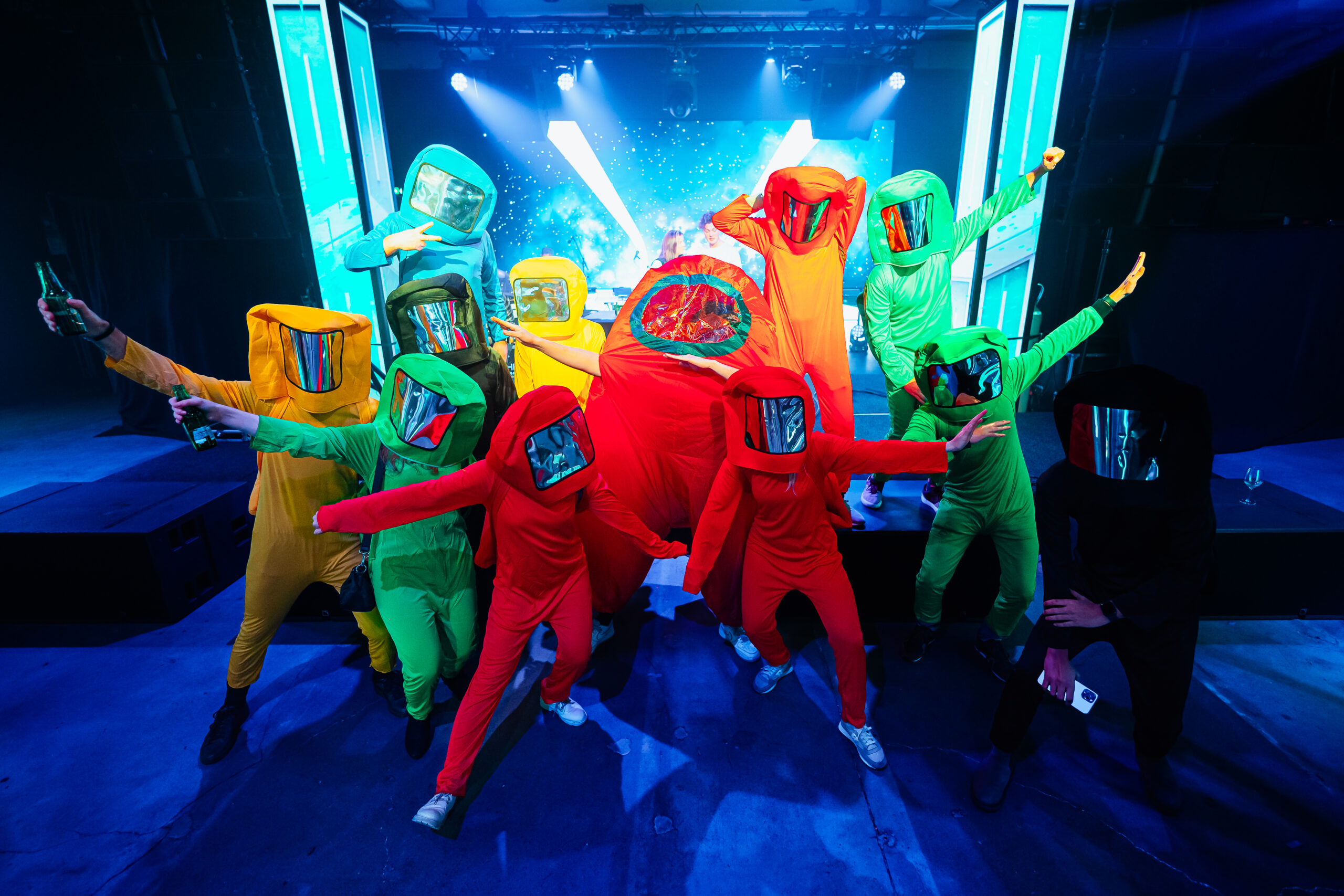 Groep gasten in kleurrijke ruimtepakken poseert tijdens een themafeest.
