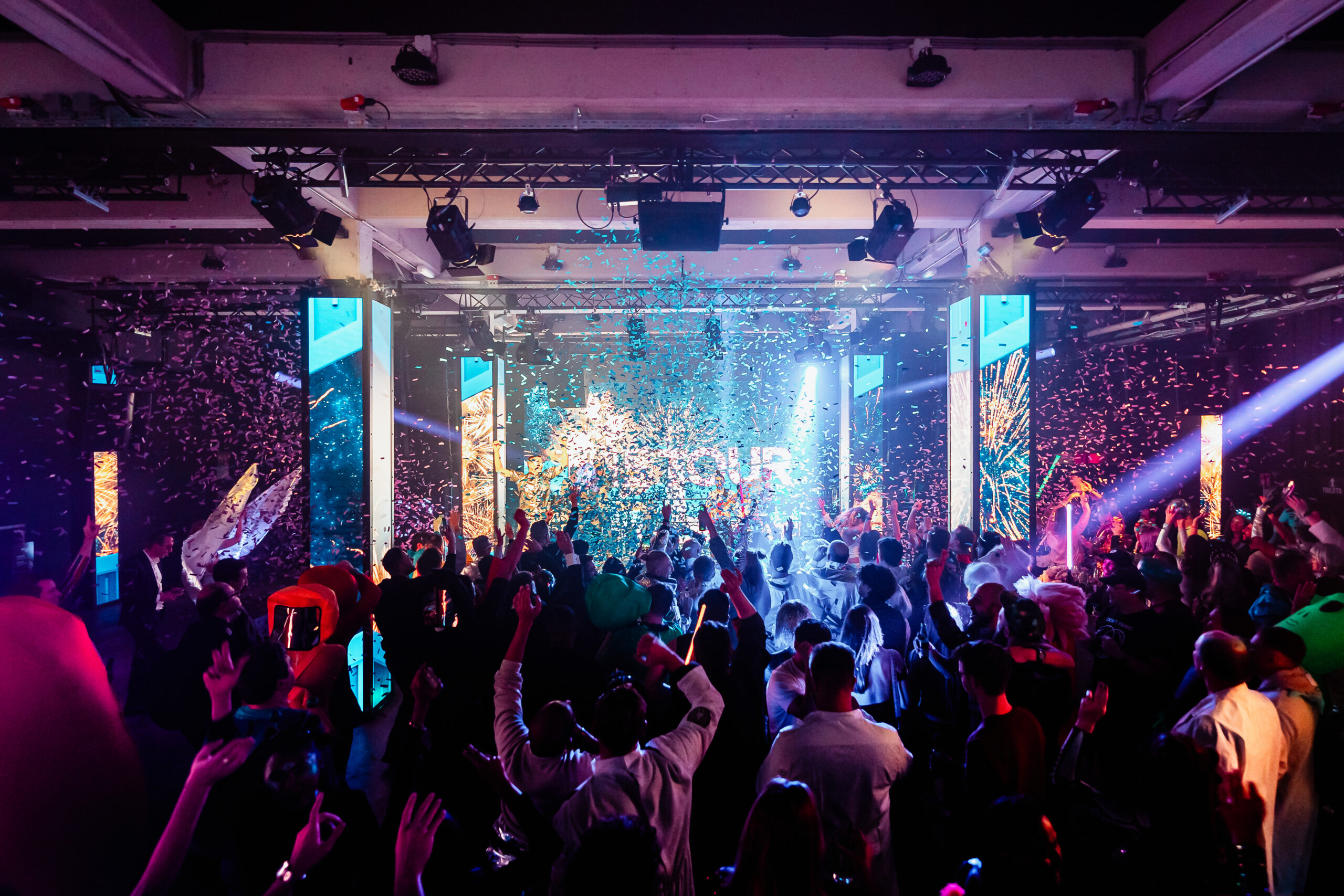 Confetti vliegt door de lucht in een zaal met futuristisch decor tijdens een themafeest.