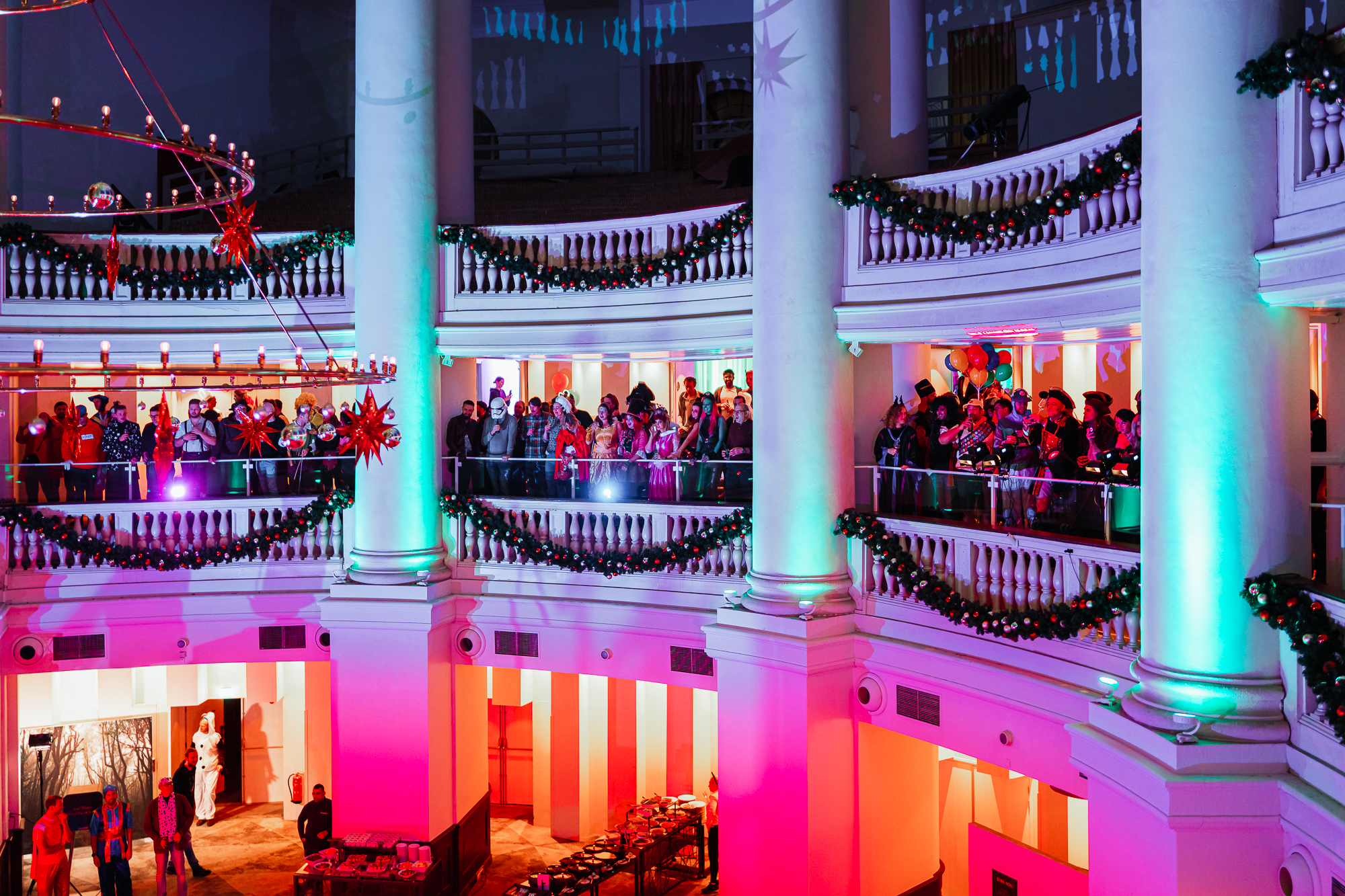 Feestelijke decoratie met kerstversiering en gasten op een balkon in een verlichte zaal met klassieke architectuur