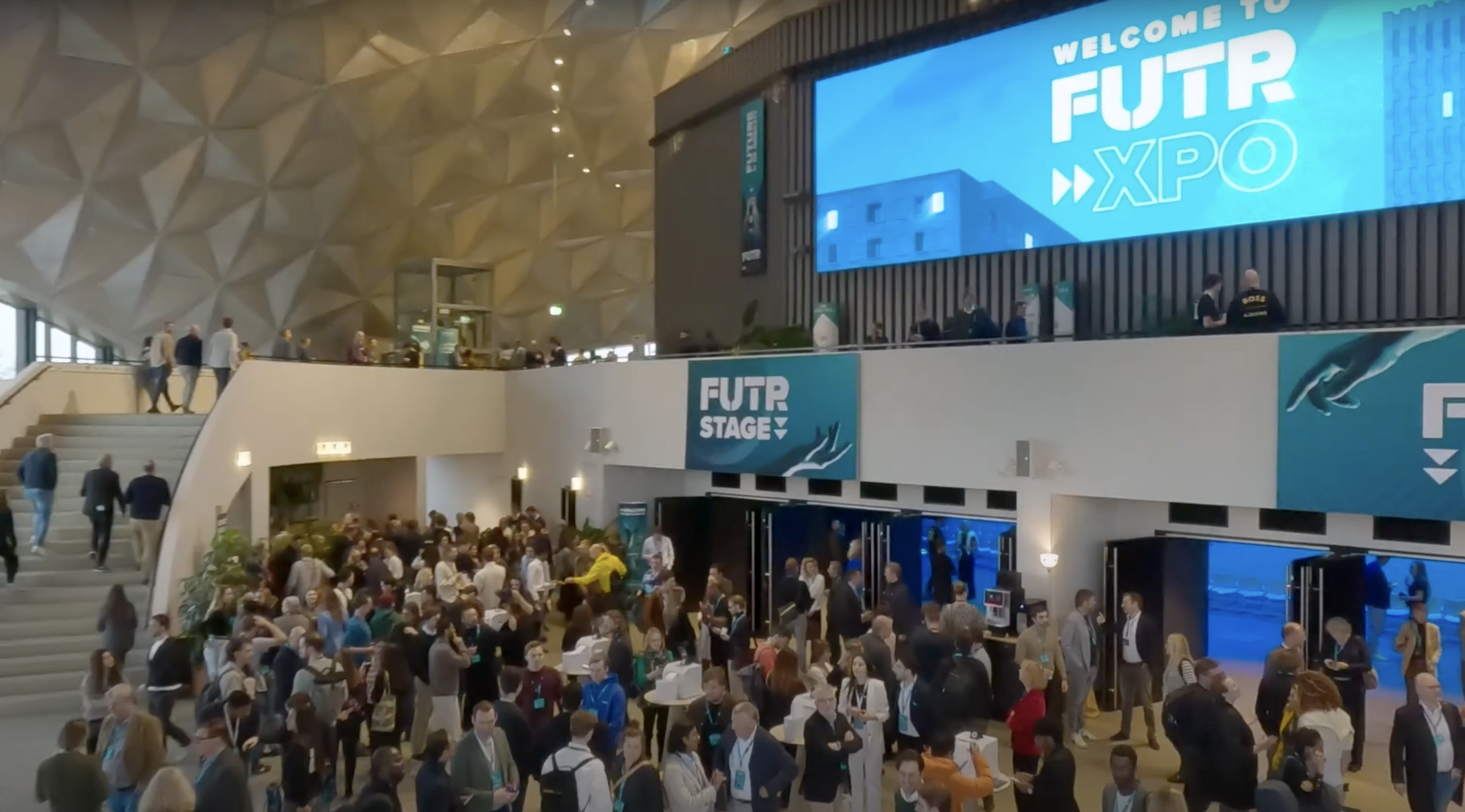 Een drukke ontvangsthal van het FUTR-evenement, gevuld met bezoekers en banners.