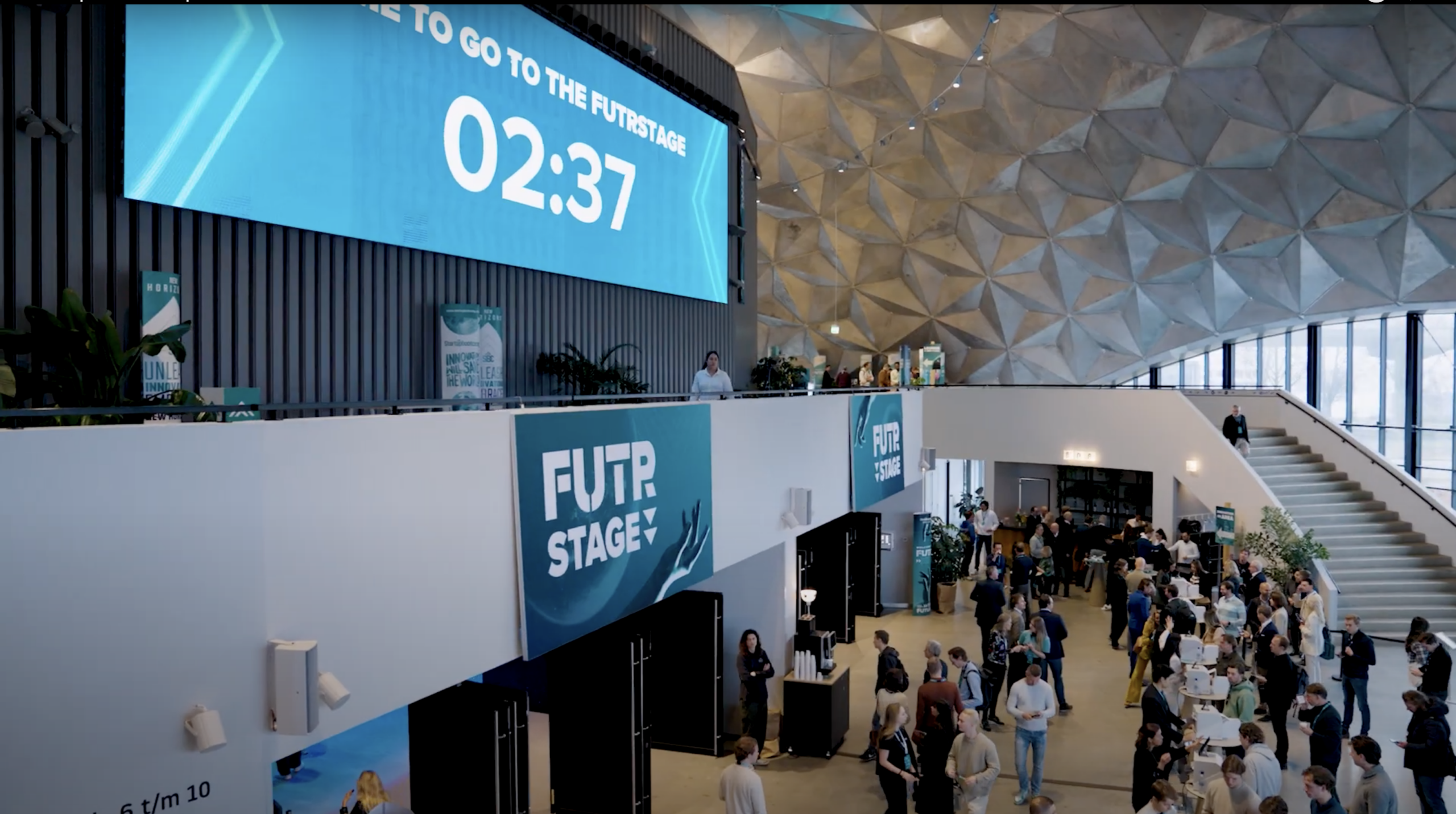 Een digitale aftelklok boven een FUTR-stage banner in een moderne evenementenhal.