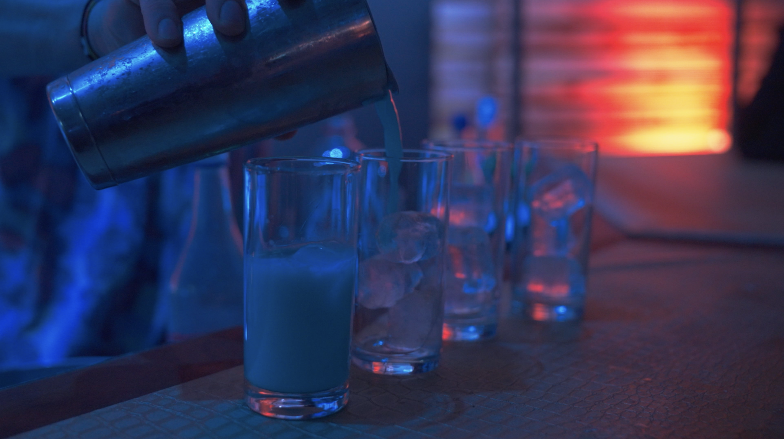 Een bartender schenkt een felgekleurde drank in glazen met ijs tijdens het evenement.